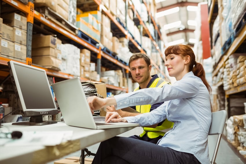 Warehouse worker and manager looking at laptop in a large warehouse-1